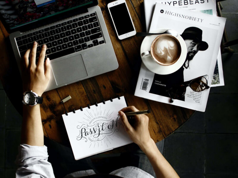 A person at their desk writing on paper using calligraphy