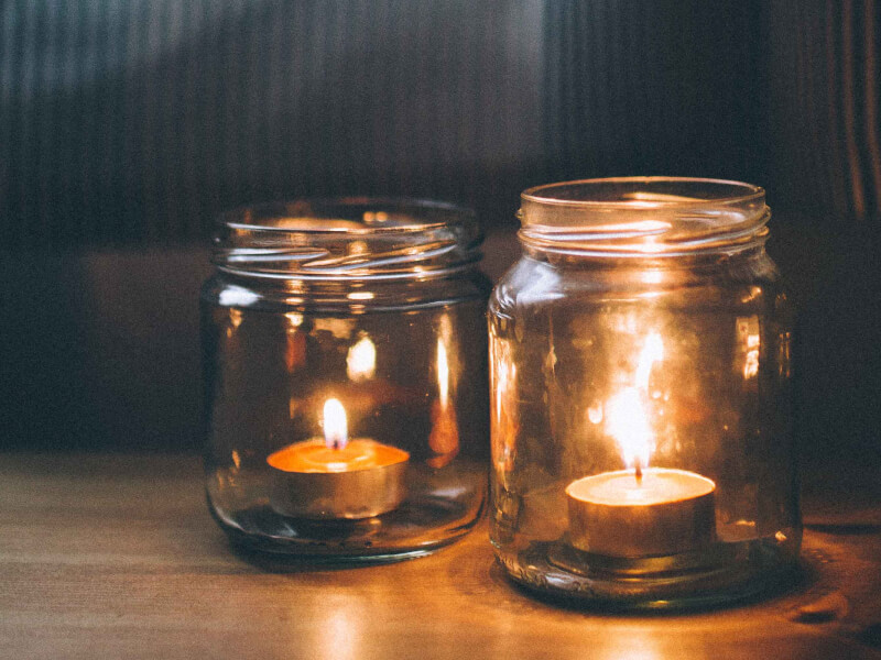 Two lit candles each in their own glass jars