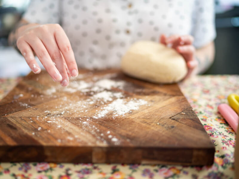 hands preparing a wooden board for kneading pasta