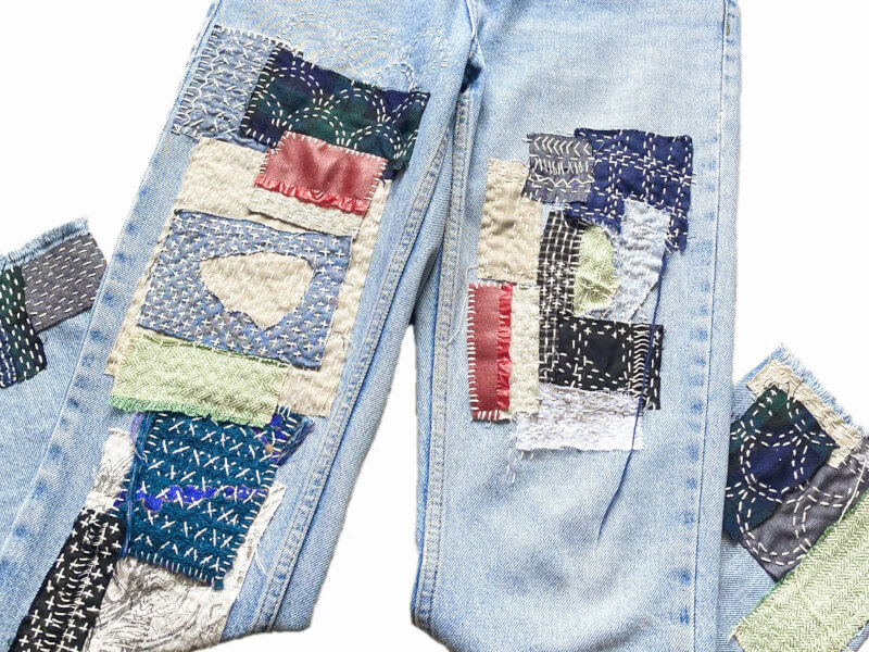 A pair of jeans, decorated with visible mending techniques