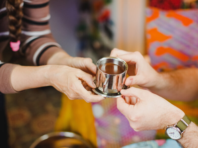Two pairs of hands holding a cup of DIY chocolate. 