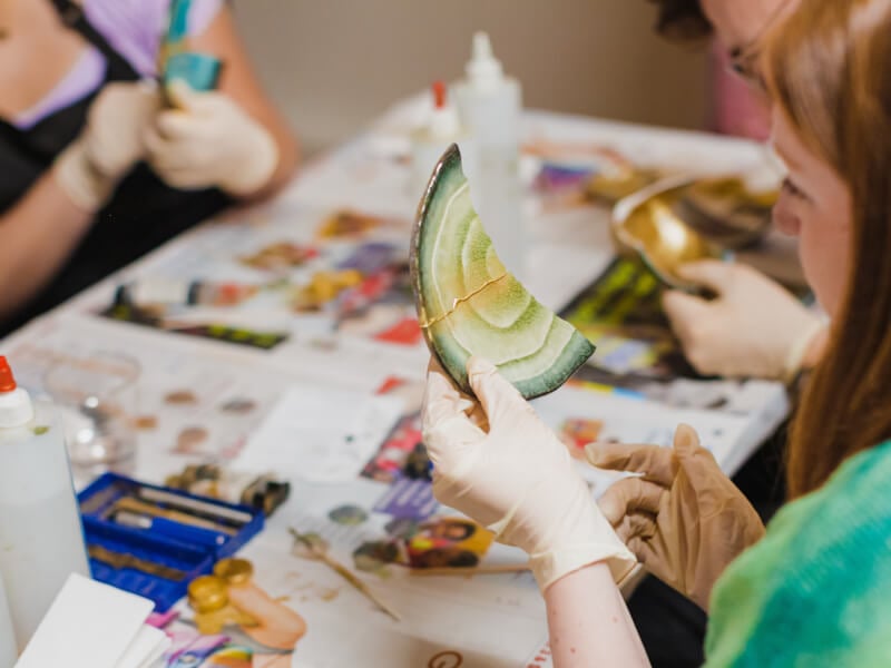 Woman wearing gloves working with pottery in a kintsugi class