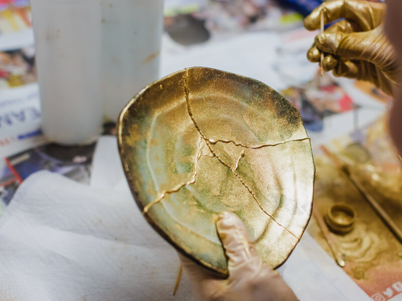 A close up of a plate being fixed with gold resin using the kintsugi technique