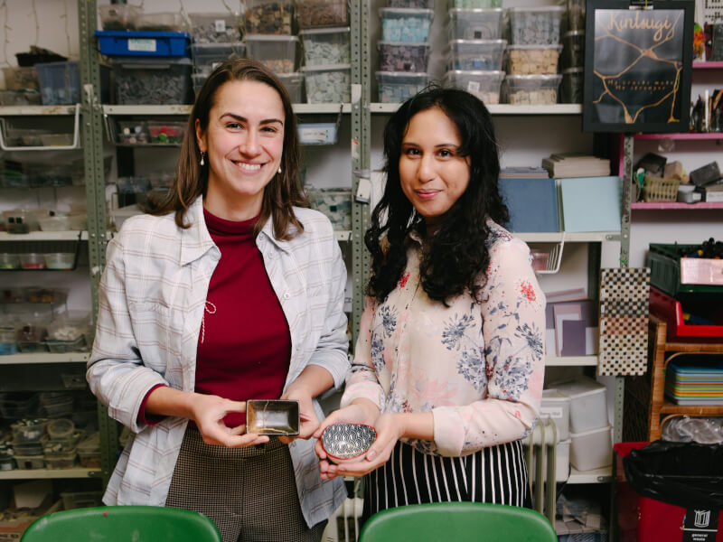 Two women are smiling and holding their finished pieces of kintsugi pottery