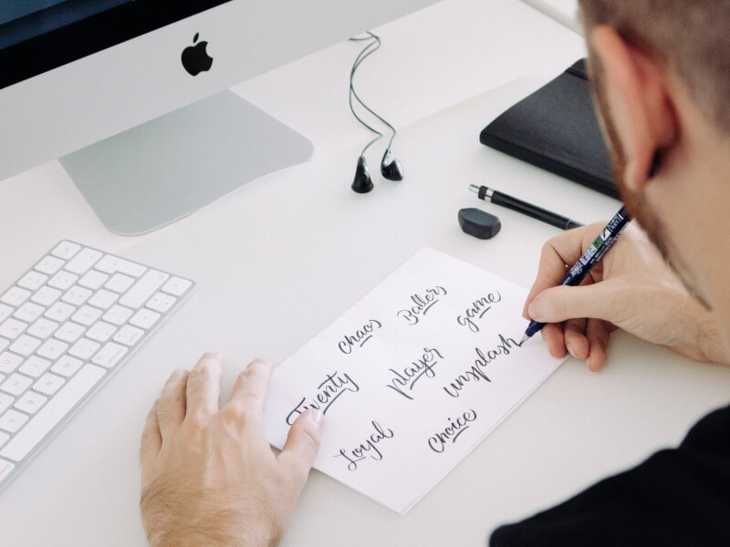A man writes some beautiful calligraphy lettering on white paper