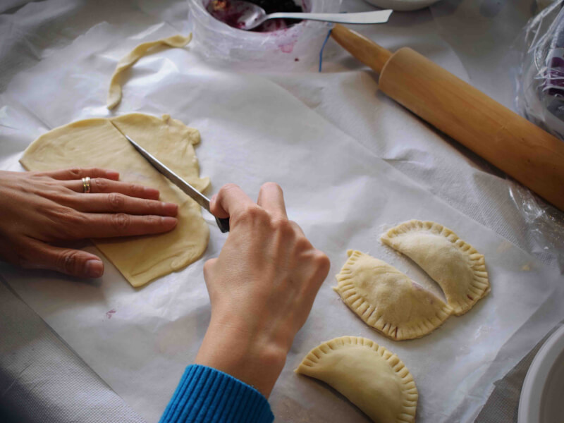 A knife cutting dough from a dumpling making kit. Three homemade dumplings are to the side. 