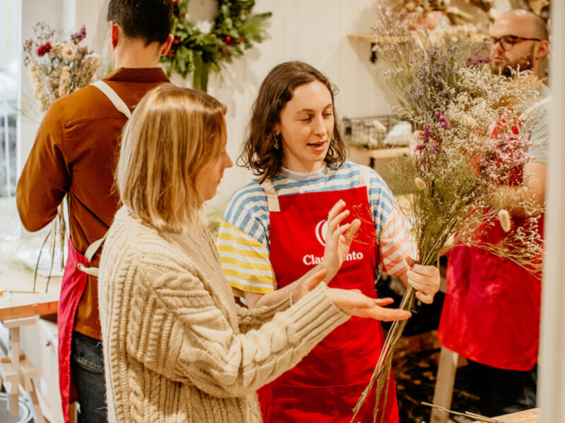 Two women look at a dried flower bouquet in a floristry class
