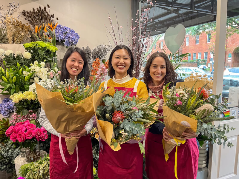 Three women holding dried flower bouquets and smiling
