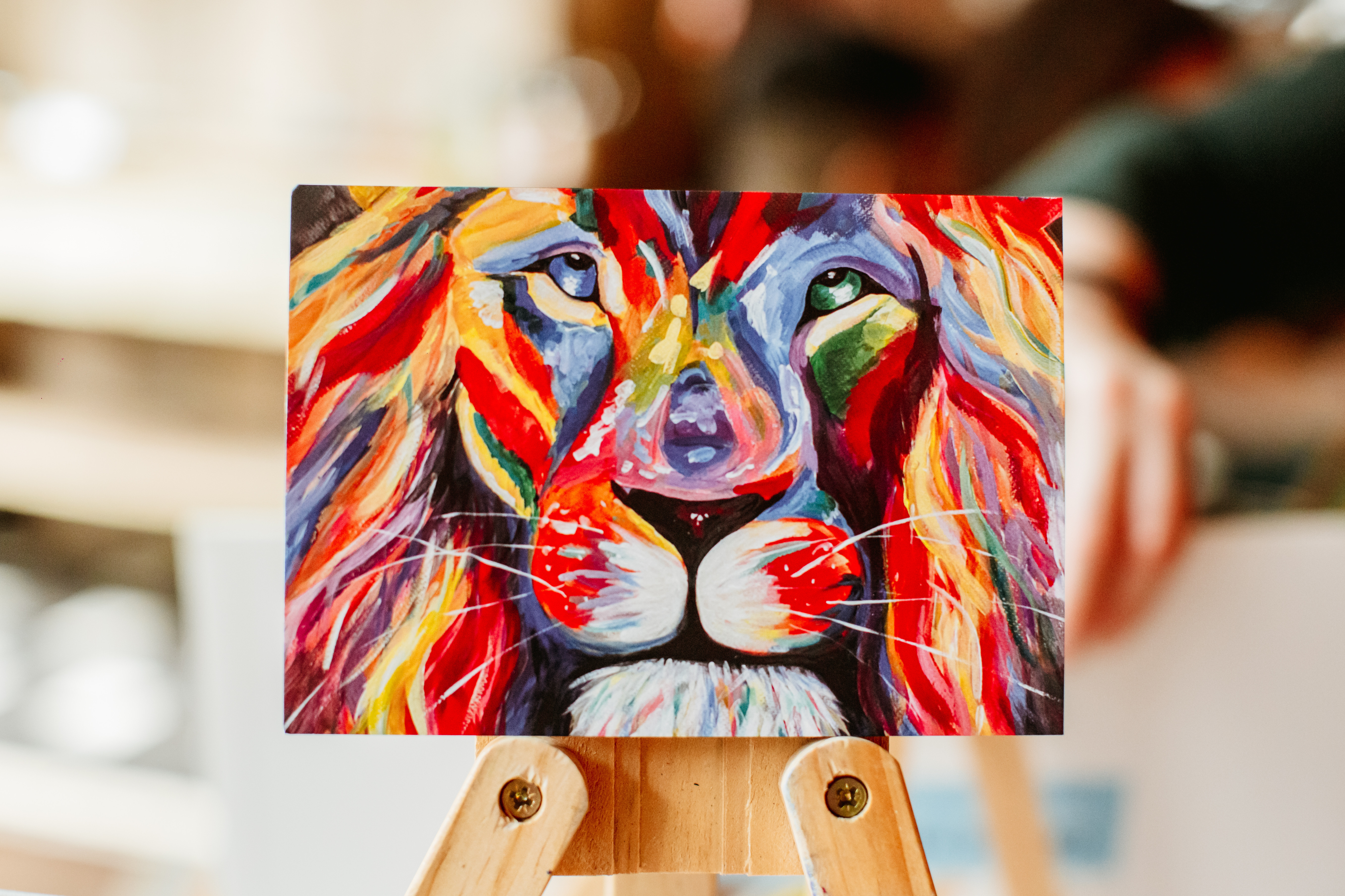 A finished painting of a multicoloured lion head on an easel