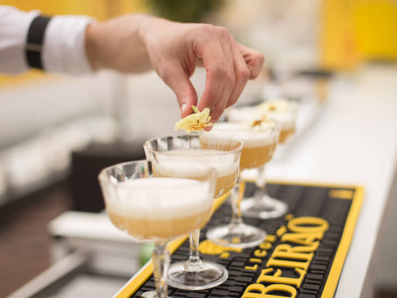 A man adds a yellow flower garnish to their DIY cocktail.