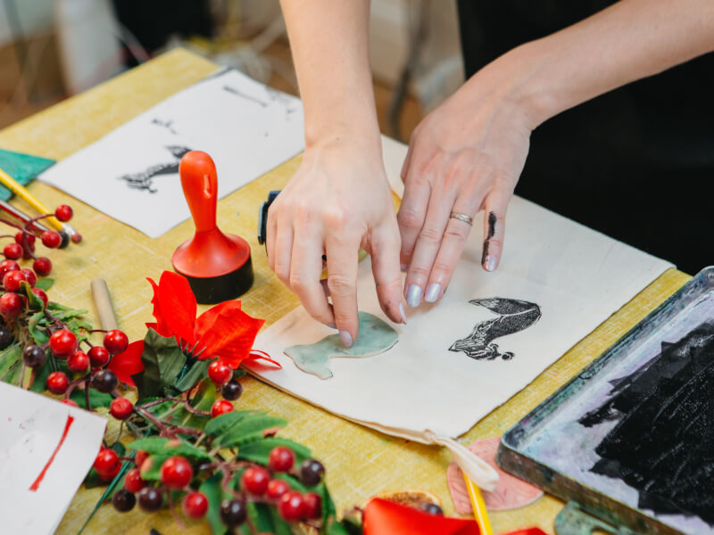 A close up of a person making a lino print Christmas card