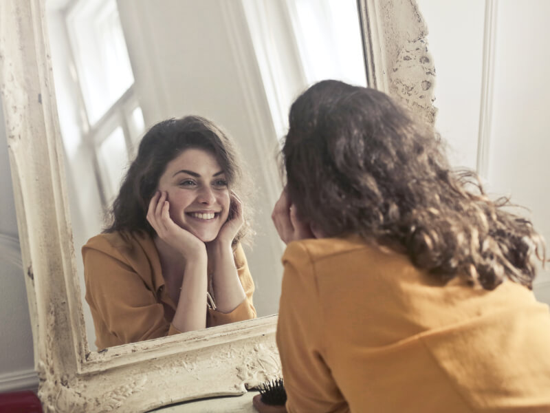 A person smiling at their reflection in a mirror
