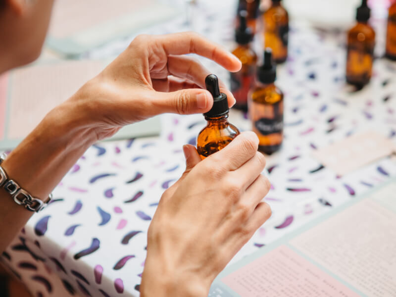 A close up of a person holding an amber bottle filled with essential oil