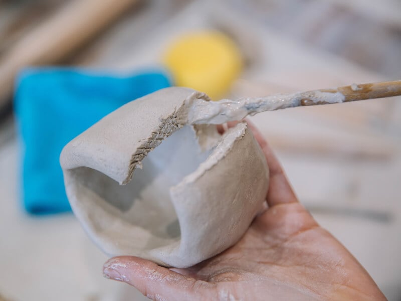 A paintbrush painting clay at a pottery class.
