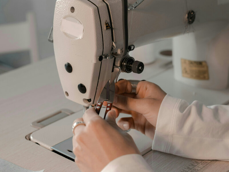 A person threading the needle on a sewing machine