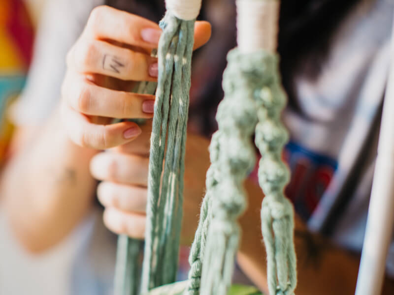 A close up of a macrame project in green cord