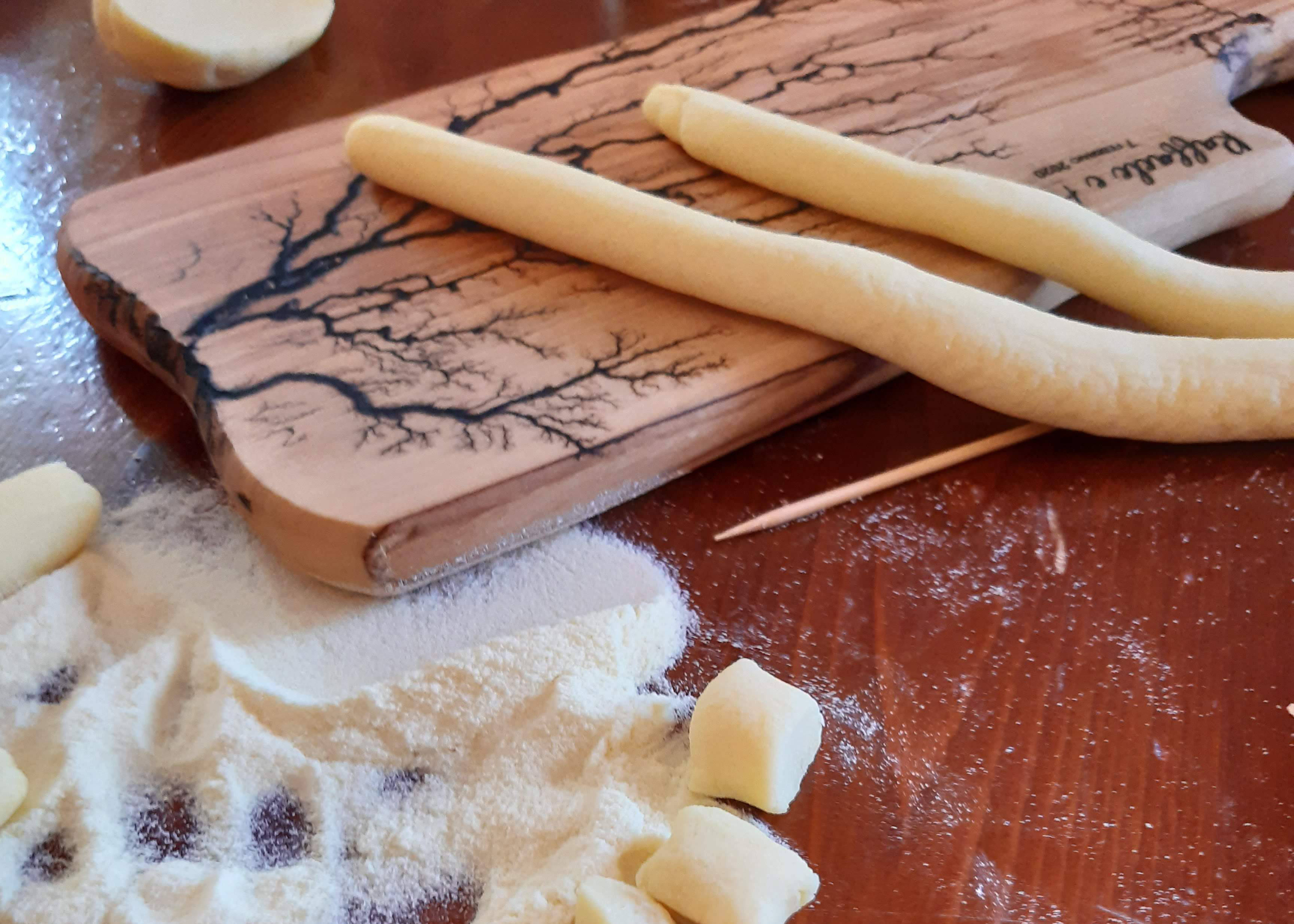 Italian pasta dough made by hand sits on a floured wooden board on a worktop