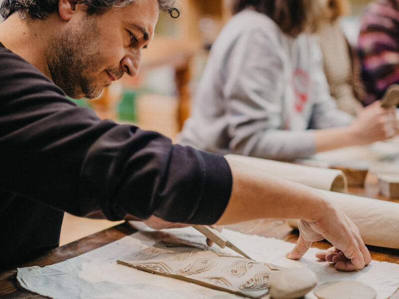 A man and a woman decorating clay pots together
