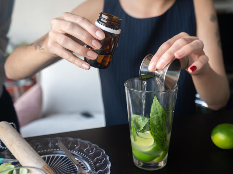 A woman is pouring a measure of spirits into a glass