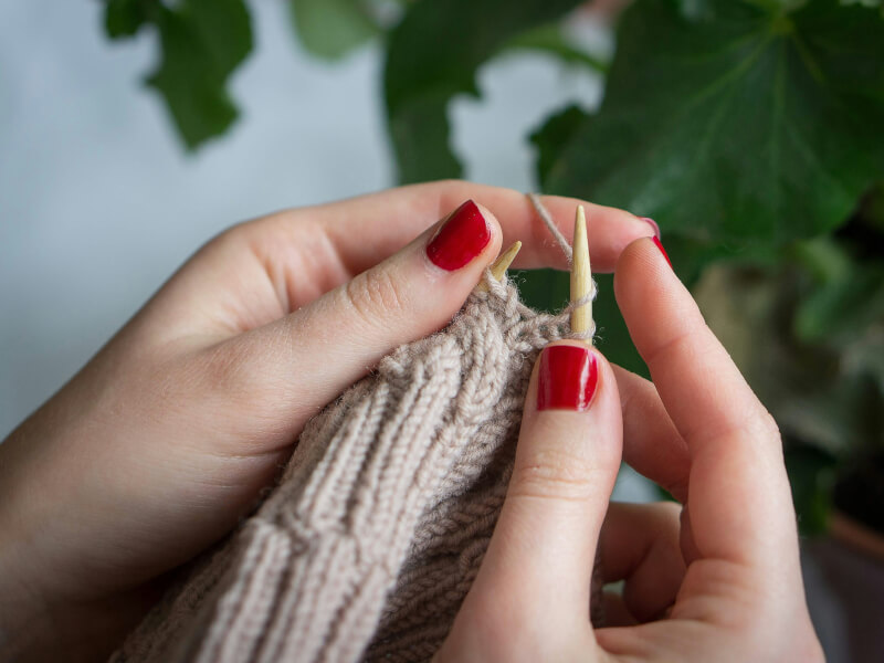 Close up of a person knitting with cream yarn