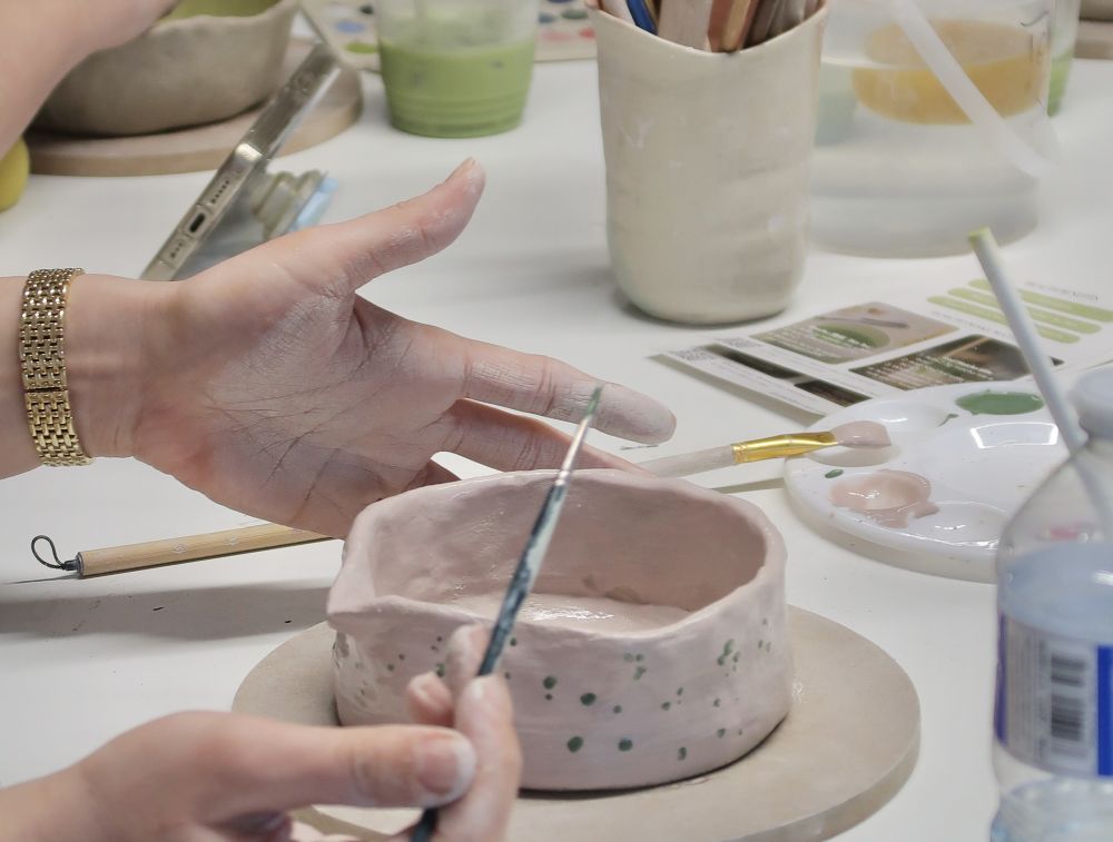 Hands painting a bowl in a pottery and matcha tasting class