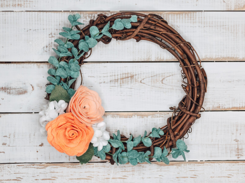 A simple wicker flower wreath with bright felted flowers
