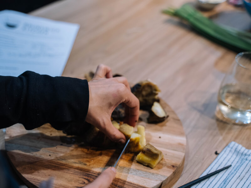 A close up shot of a person chopping vegetables on a wooden chopping board