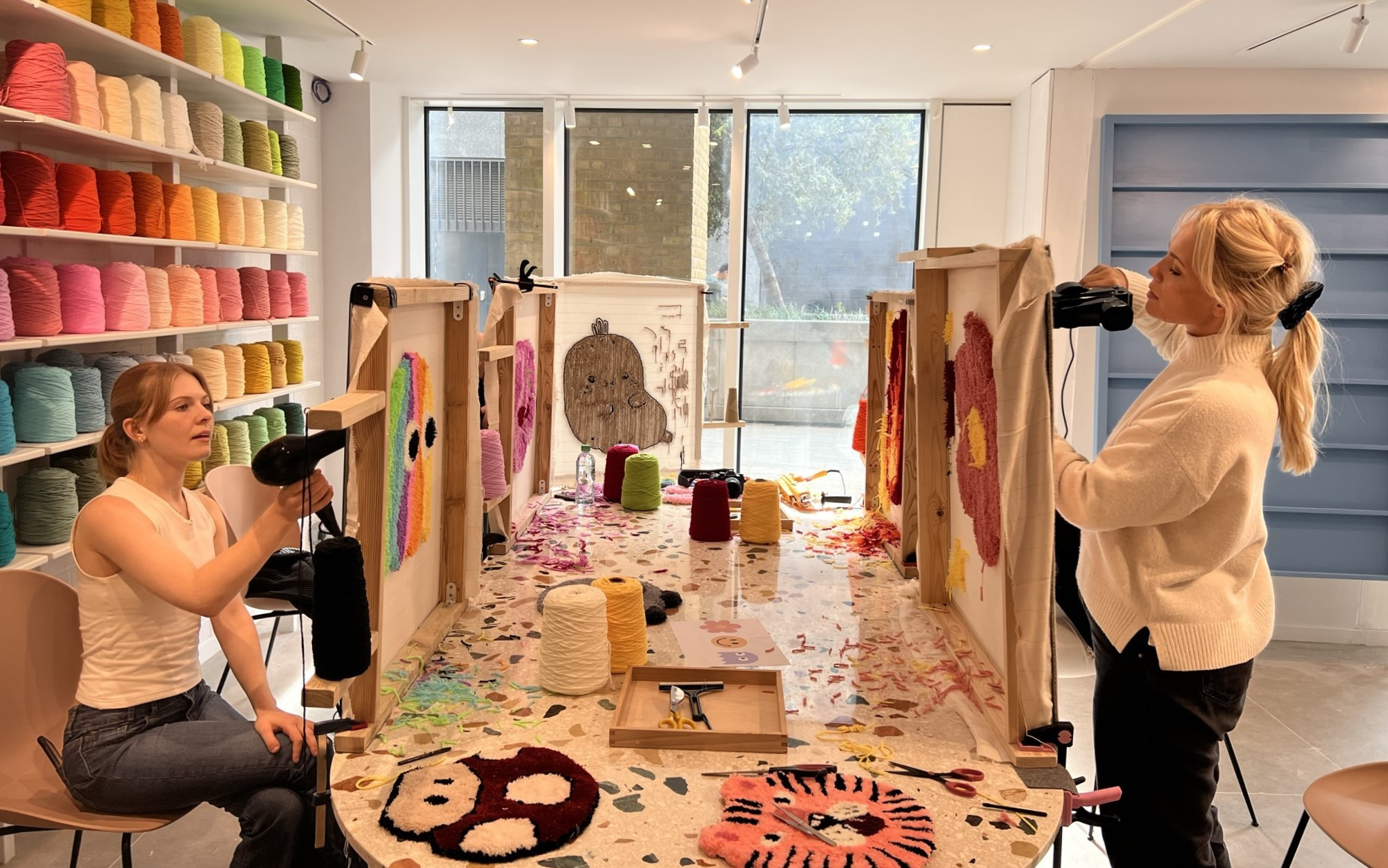 Two women at a Tufting London workshop are working on tufting designs