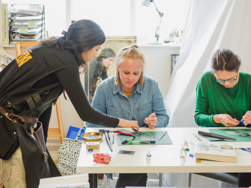 A teacher is showing two students how to make wax moulds at a jewellery making course in Manchester 