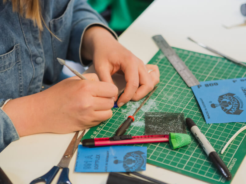 A close up of a person working on a wax mould at a jewellery making class