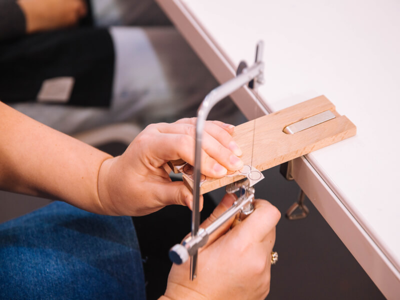 A close up of a person sawing a template at a jewellery making course