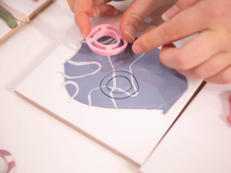 A close up of a person cutting out shapes from polymer clay 