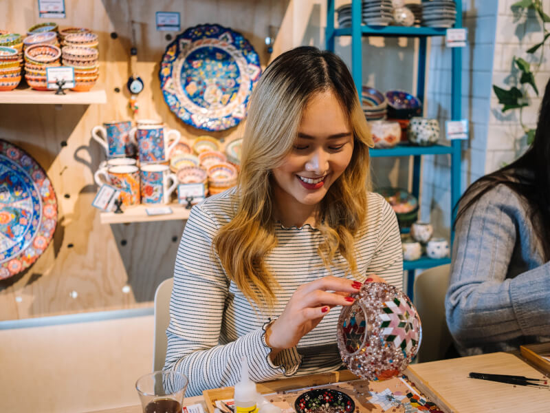 A woman making a mosaic project using colourful tiles