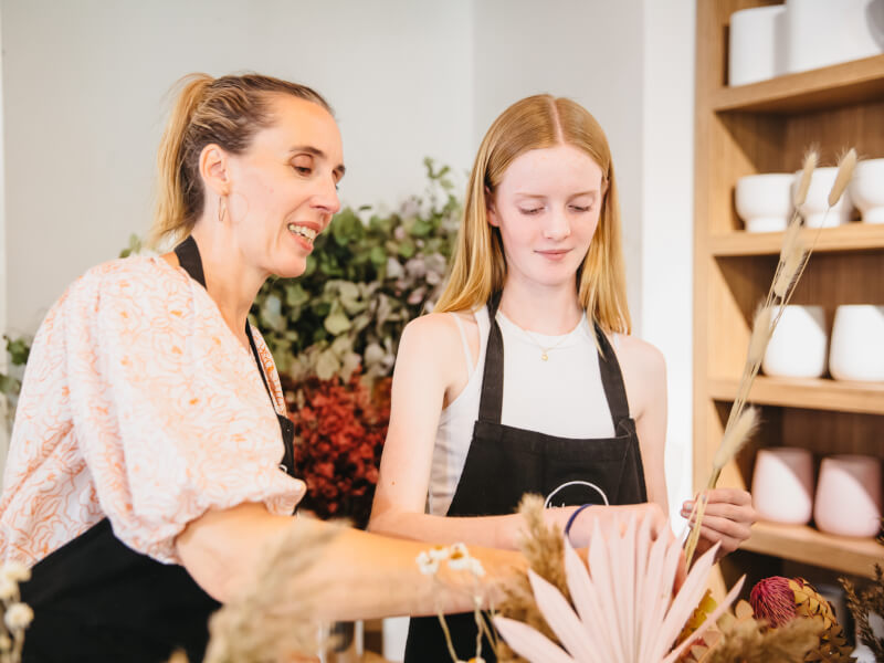 A mother and daughter are arranging dried flowers at a Mother's Day floristry workshop