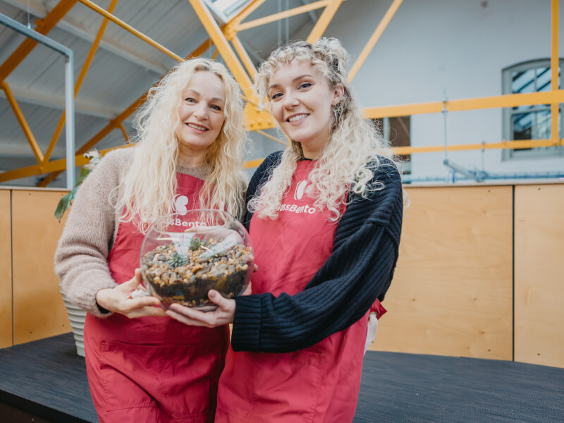 A mother and daughter hold a glass terrarium at a Mother's Day workshop 