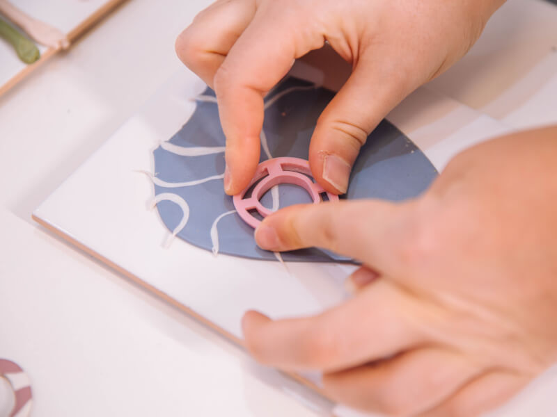 A close up of a person cutting out polymer clay with a shape cutter