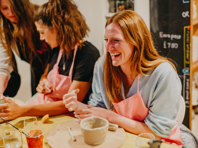 A group of women are laughing at a hand building pottery class at the M.Y.O studio in London