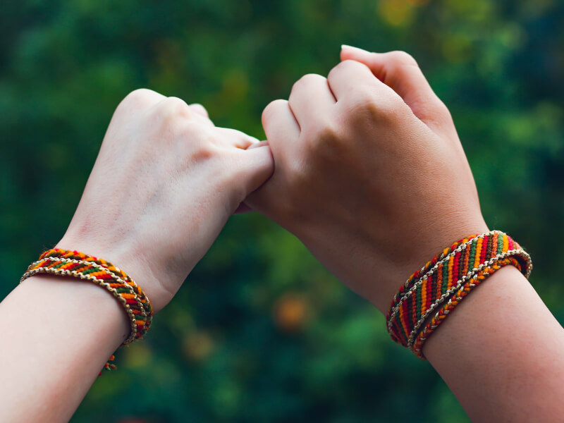 People make a pinky promise whilst wearing matching DIY braided bracelets.
