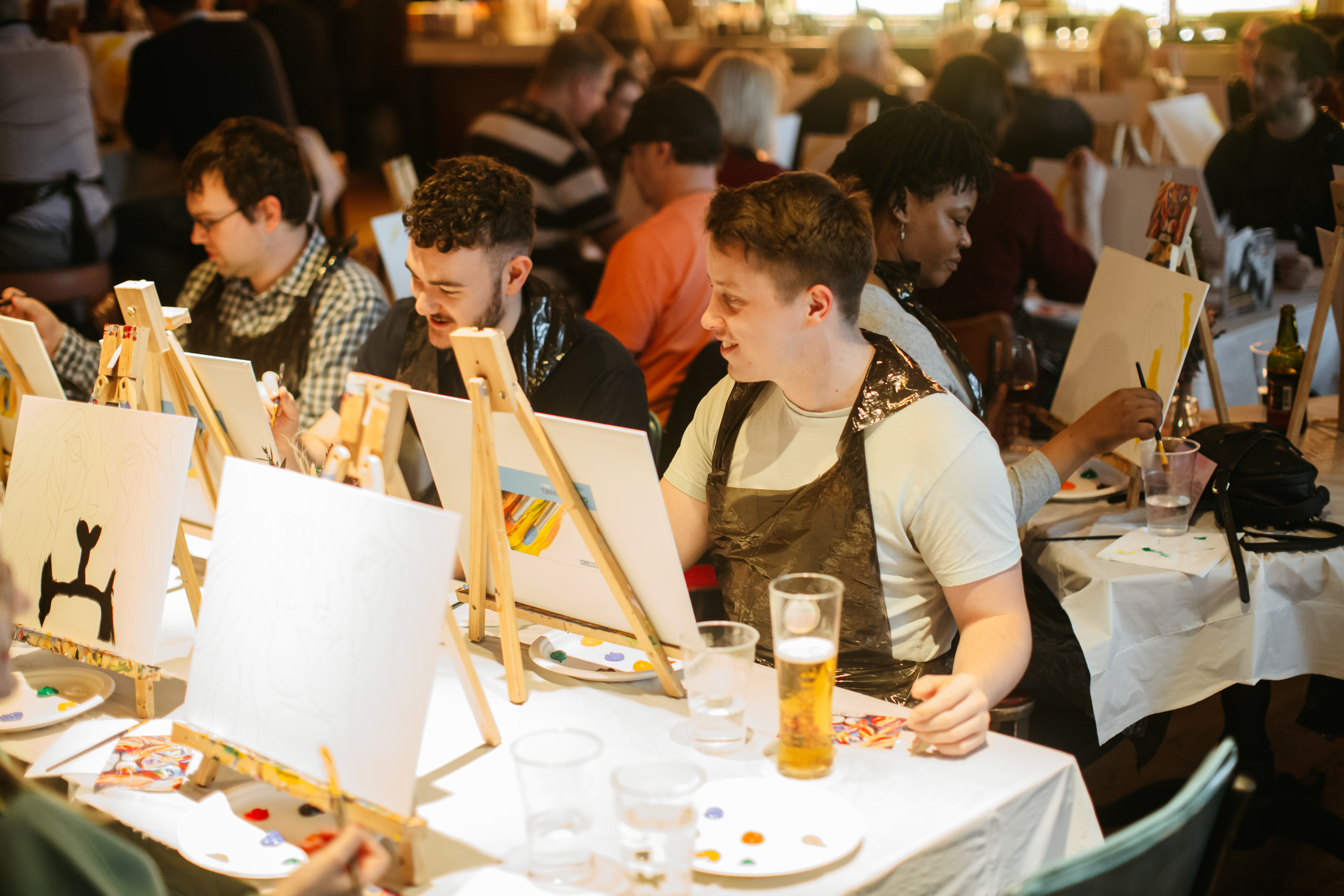 A group of people sitting at easels at a paint and sip workshop