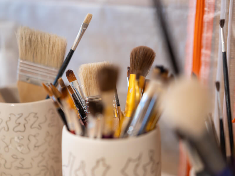 A selection of paintbrushes in two beige ceramic pots
