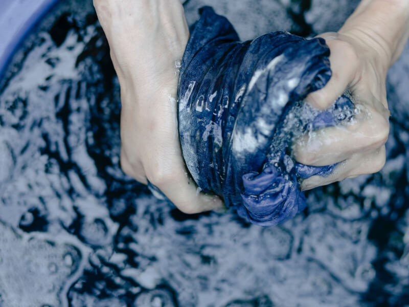 Pair of hands wringing blue dye out of a piece of fabric