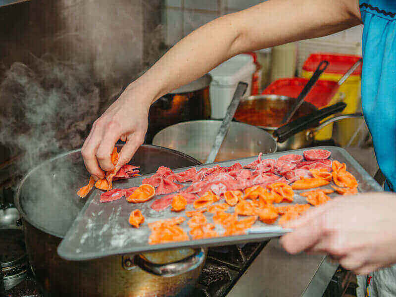 Someone putting handmade pasta shapes into a pan. 