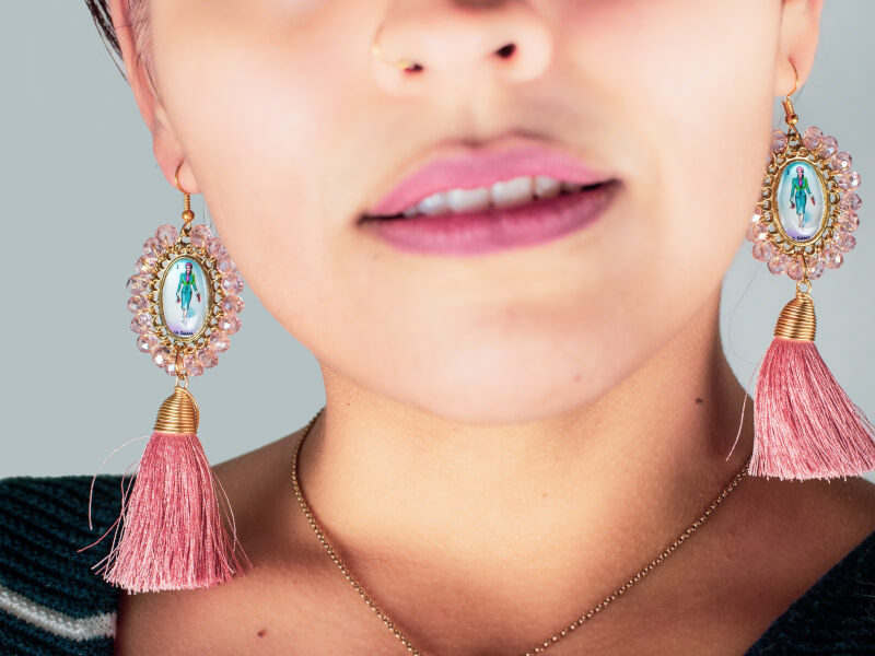 Ornate pink and gold DIY earrings, decorated with gems and tassels, hang from a woman's ears.