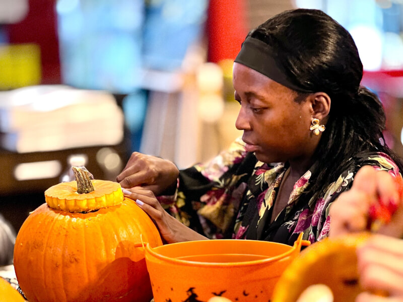 A person cutting the top off of a pumpkin, ready to carve