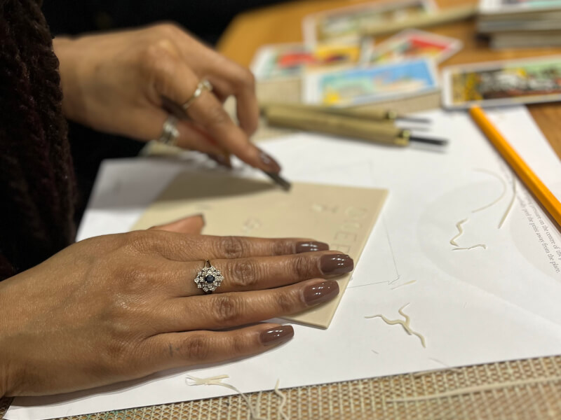 A close up of a woman carving a design into a lino block for printing