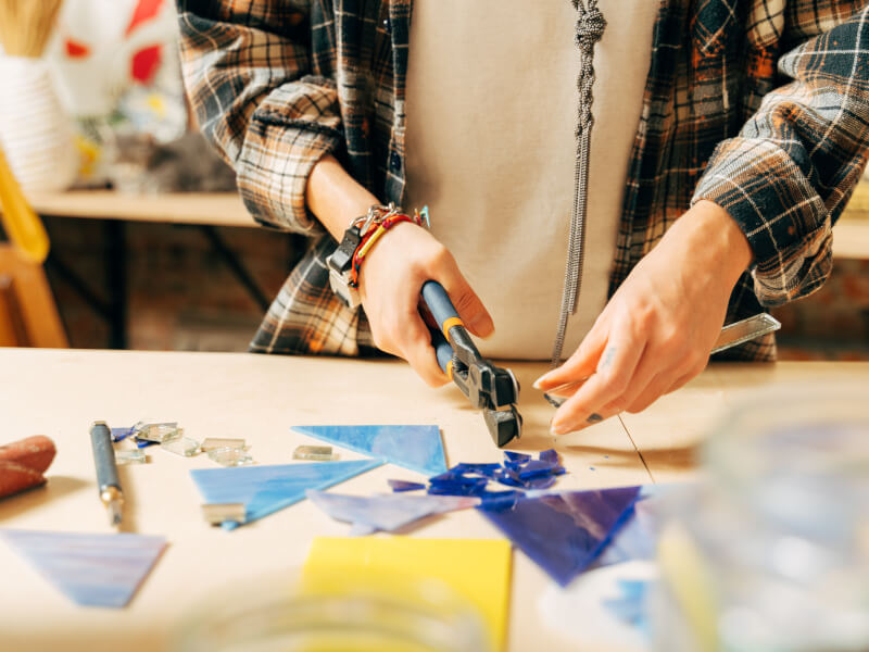Person in a checked shirt cutting glass for a fusing project