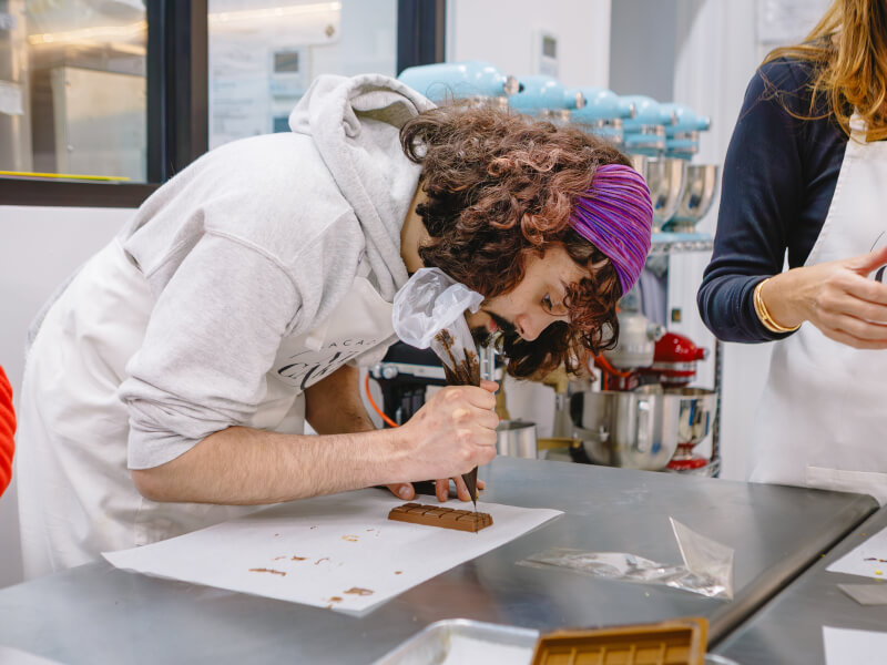 A person is decorating a bar of handmade chocolate