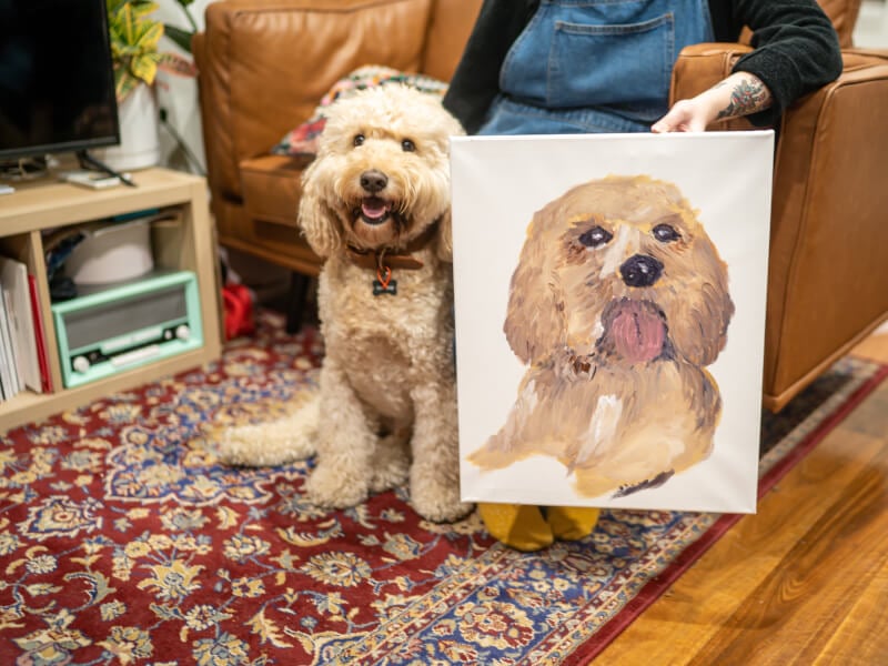Dog posing with their portrait from a painting class