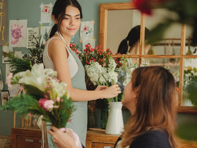 Two people talking whilst making floral arrangements