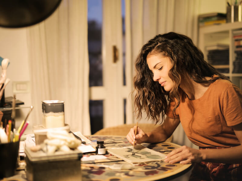 A person concentrating as they create a piece of watercolour art